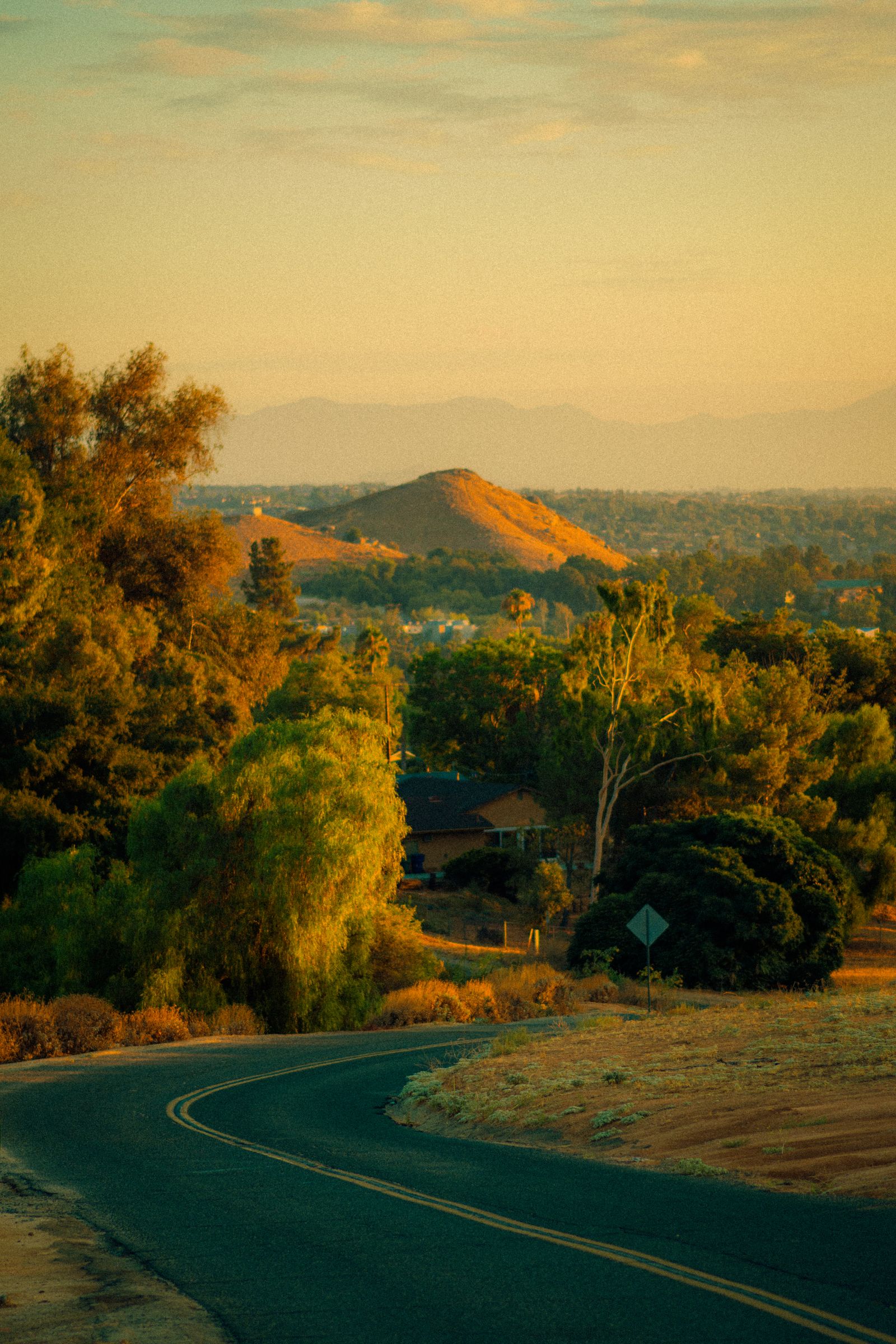 Southern California hillside neighborhood at golden hour with dry brush