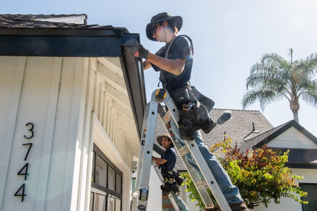 Solutionist installing gutters on a white estate home