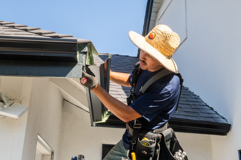 Solutionist fitting a gutter section on a Los Angeles roofline