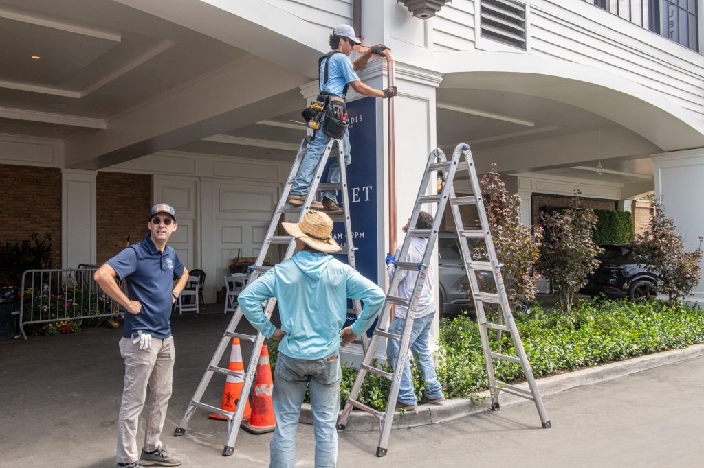 Two ladders set under a covered entry for a downspout run