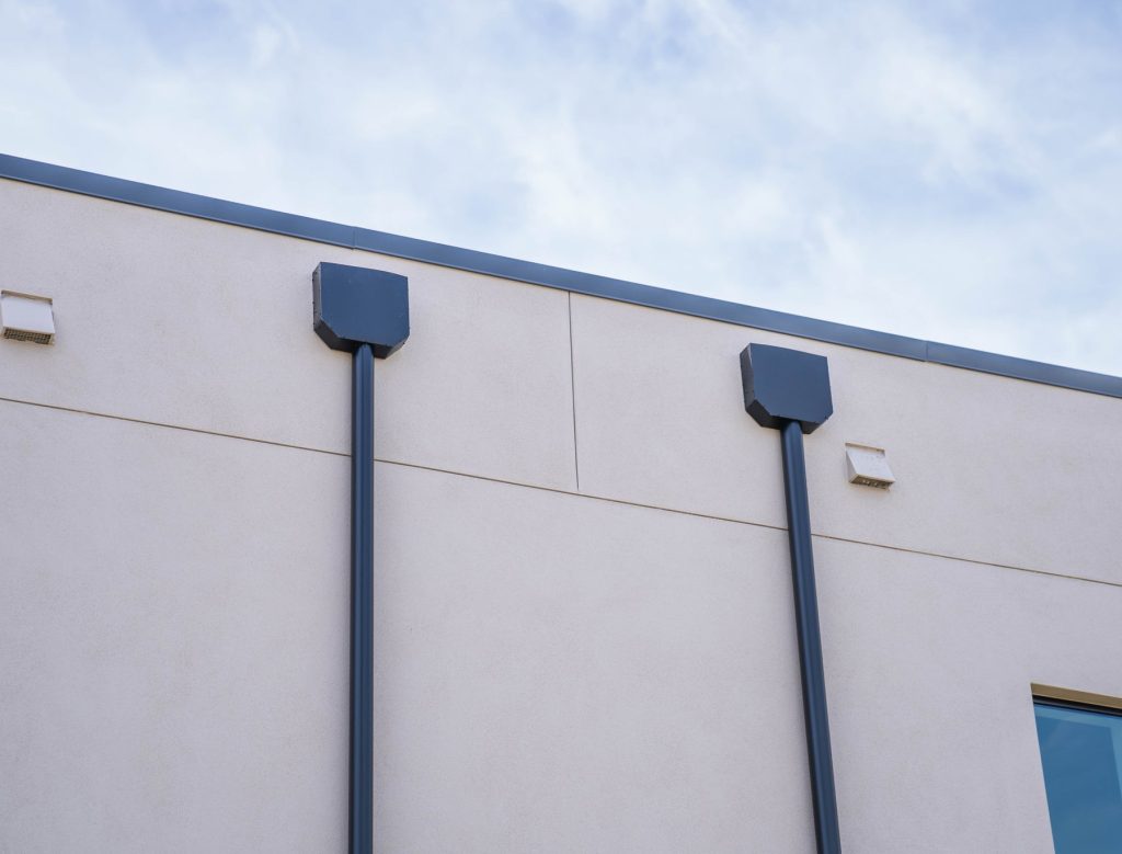 Dark scuppers and downspouts on a smooth wall